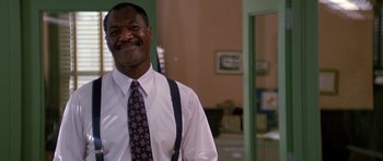 Movie still from “The Hard Way” (1991), directed by John Badham – A man in a white dress shirt and a tie smiling; Medium shot, Low angle