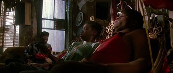 Movie still from “The Hard Way” (1991), directed by John Badham – Two people are sitting on a couch and one of them is using a cell phone; Medium shot, Low angle