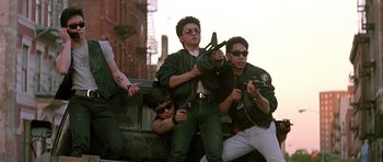 Movie still from “The Hard Way” (1991), directed by John Badham – A group of young men standing next to each other on the side of the road; Medium shot, Low angle