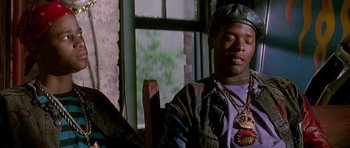 Movie still from “The Hard Way” (1991), directed by John Badham – A man sitting in front of a window wearing a hat; Close Up shot, Low angle