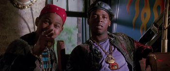 Movie still from “The Hard Way” (1991), directed by John Badham – A couple of men sitting next to each other on top of a table; Close Up shot, Low angle