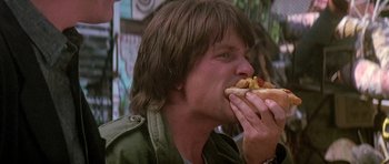 Movie still from “The Hard Way” (1991), directed by John Badham – A man eating a hot dog on top of a hot dog bun; Close Up shot, Low angle