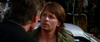 Movie still from “The Hard Way” (1991), directed by John Badham – A man with long brown hair talking to another man; Close Up shot, Over the shoulder angle