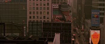 Movie still from “The Hard Way” (1991), directed by John Badham – An advertisement of a man smoking a cigarette on top of a building; Wide shot, Low angle