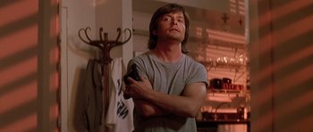 Movie still from “The Hard Way” (1991), directed by John Badham – A man holding a nintendo wii game controller in his hands; Medium shot, Low angle