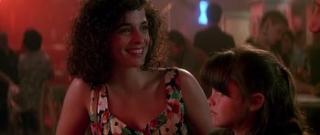 Movie still from “The Hard Way” (1991), directed by John Badham – A woman and a child are smiling for the camera; Close Up shot, Over the shoulder angle