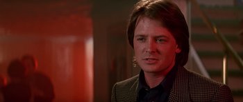 Movie still from “The Hard Way” (1991), directed by John Badham – A man with long hair wearing a suit and tie; Close Up shot, Over the shoulder angle