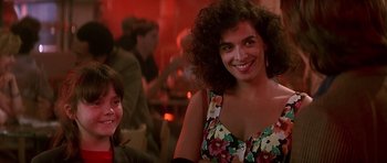 Movie still from “The Hard Way” (1991), directed by John Badham – A woman with curly brown hair smiling at the camera; Close Up shot, Over the shoulder angle