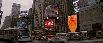 Movie still from “The Hard Way” (1991), directed by John Badham – A large billboard on the side of a building in a city; Wide shot, Low angle