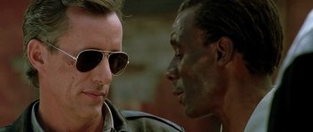 Movie still from “The Hard Way” (1991), directed by John Badham – A man in sunglasses and a man in a military jacket; Close Up shot, Over the shoulder angle