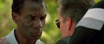 Movie still from “The Hard Way” (1991), directed by John Badham – Two men are talking to each other in a park; Close Up shot, Low angle