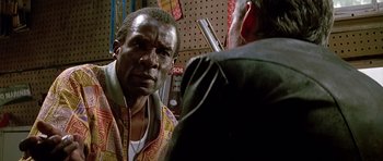 Movie still from “The Hard Way” (1991), directed by John Badham – A man is talking to another man in a store; Close Up shot, Over the shoulder angle