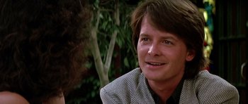 Movie still from “The Hard Way” (1991), directed by John Badham – A person wearing a suit and smiling; Close Up shot, Over the shoulder angle