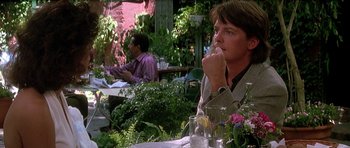 Movie still from “The Hard Way” (1991), directed by John Badham – A man sitting at an outdoor table in a restaurant; Medium shot, Over the shoulder angle