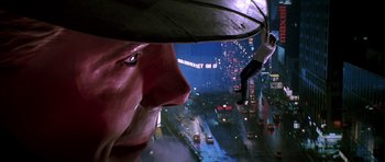 Movie still from “The Hard Way” (1991), directed by John Badham – A man with an umbrella looking out a window at a city; Wide shot, Low angle