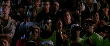 Movie still from “The Hard Way” (1991), directed by John Badham – A group of people sitting in a stadium watching a football game; Medium shot, High angle