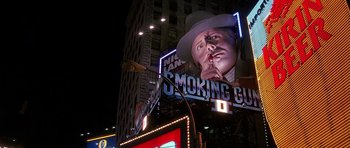 Movie still from “The Hard Way” (1991), directed by John Badham – A billboard of a man smoking a cigarette in the middle of the night; Wide shot, Low angle