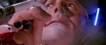 Movie still from “The Hard Way” (1991), directed by John Badham – A man is using an electronic device to make a face; Extreme Close Up shot, Low angle