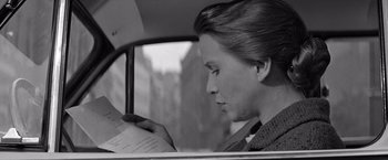 Movie still from “The Haunting” (1963), directed by Robert Wise – A woman sitting in the back of a car reading a book; Close Up shot, Over the shoulder angle