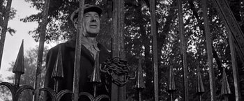 Movie still from “The Haunting” (1963), directed by Robert Wise – An old man standing behind a metal fence; Medium shot, Low angle