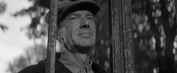 Movie still from “The Haunting” (1963), directed by Robert Wise – An older man wearing a hat looking out of a window; Close Up shot, Low angle