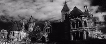 Movie still from “The Haunting” (1963), directed by Robert Wise – A black and white photo of a building with a cloudy sky in the background; Extreme Wide shot, Low angle