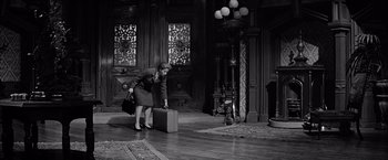 Movie still from “The Haunting” (1963), directed by Robert Wise – A woman is bending over a suit case; Wide shot, High angle