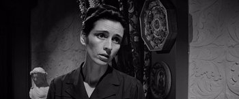 Movie still from “The Haunting” (1963), directed by Robert Wise – Black and white photograph of a woman in front of wall hangings; Close Up shot, Low angle