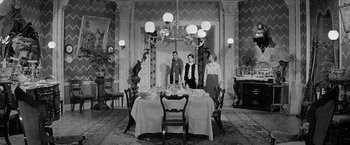 Movie still from “The Haunting” (1963), directed by Robert Wise – A group of people standing around a dining room table; Wide shot, High angle