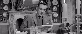 Movie still from “The Haunting” (1963), directed by Robert Wise – A man sitting at a table looking at a paper; Close Up shot, Over the shoulder angle