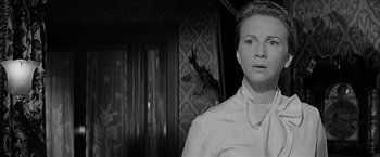 Movie still from “The Haunting” (1963), directed by Robert Wise – A woman wearing a white shirt standing in front of a door; Close Up shot, Low angle