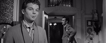 Movie still from “The Haunting” (1963), directed by Robert Wise – A black - and - white photo of a man in a suit and tie; Close Up shot, Over the shoulder angle