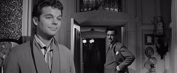 Movie still from “The Haunting” (1963), directed by Robert Wise – A man standing next to another man in front of a door; Medium shot, Over the shoulder angle