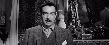 Movie still from “The Haunting” (1963), directed by Robert Wise – A man in a suit and tie standing in front of a vase; Close Up shot, Over the shoulder angle