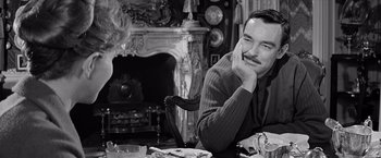 Movie still from “The Haunting” (1963), directed by Robert Wise – A black and white photo of a man sitting in front of a fireplace; Close Up shot, Over the shoulder angle