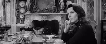 Movie still from “The Haunting” (1963), directed by Robert Wise – A woman sitting at a table with a cup of tea; Medium shot, Over the shoulder angle