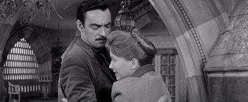 Movie still from “The Haunting” (1963), directed by Robert Wise – A man and a woman embracing each other in front of a chandelier; Medium shot, Low angle