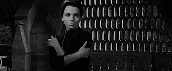 Movie still from “The Haunting” (1963), directed by Robert Wise – Black and white photograph of a woman in front of a wall; Medium shot, Low angle