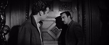 Movie still from “The Haunting” (1963), directed by Robert Wise – Two men standing next to each other in front of a door; Medium shot, Over the shoulder angle