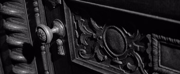 Movie still from “The Haunting” (1963), directed by Robert Wise – An ornate wooden door with a knob on the handle; Extreme Close Up shot, High angle