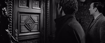 Movie still from “The Haunting” (1963), directed by Robert Wise – A man standing in front of a wooden door; Close Up shot, Over the shoulder angle