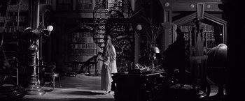 Movie still from “The Haunting” (1963), directed by Robert Wise – A woman standing in front of a table in a room; Wide shot, Low angle