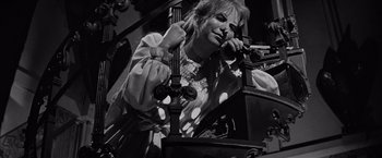 Movie still from “The Haunting” (1963), directed by Robert Wise – A woman is talking on the phone while sitting in a chair; Medium shot, Low angle
