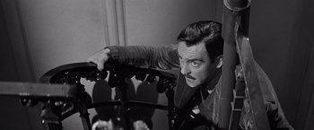 Movie still from “The Haunting” (1963), directed by Robert Wise – A black and white photo of a man leaning on a railing; Close Up shot, Low angle