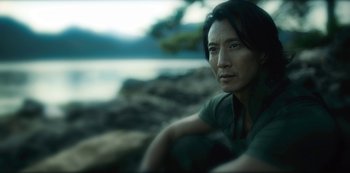 Movie still from “Altered Carbon” (2018), created by Laeta Kalogridis – A man sitting on a rock near a body of water; Close Up shot, High angle