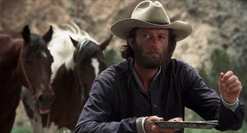Movie still from “The Hired Hand” (1971), directed by Peter Fonda – A man in a cowboy hat is holding a cell phone; Medium shot, Over the shoulder angle