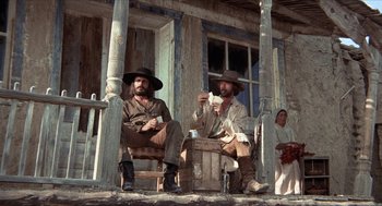Movie still from “The Hired Hand” (1971), directed by Peter Fonda – A couple of men sitting on top of a wooden bench; Wide shot, Low angle