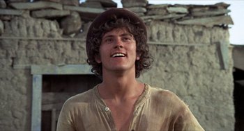 Movie still from “The Hired Hand” (1971), directed by Peter Fonda – A young man with a hat on smiling for the camera; Close Up shot, Low angle