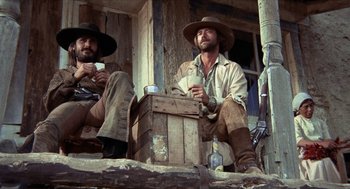Movie still from “The Hired Hand” (1971), directed by Peter Fonda – A couple of men sitting next to each other on a porch; Medium shot, Low angle
