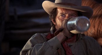 Movie still from “The Hired Hand” (1971), directed by Peter Fonda – A man in a cowboy hat drinking out of a cup; Close Up shot, Low angle